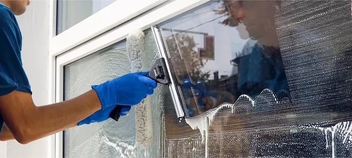 Close-up of a squeegee clearing soap off a window